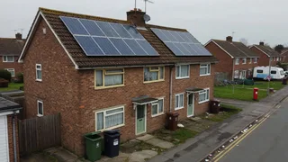 UK semi-detached house with an older rooftop solar array on a suburban street